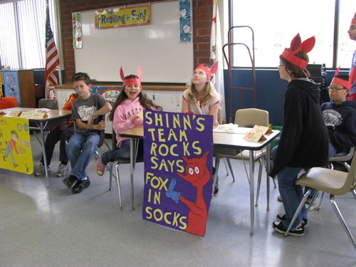 4 students sitting at a table in dr. seuss outfits during a trivia contest